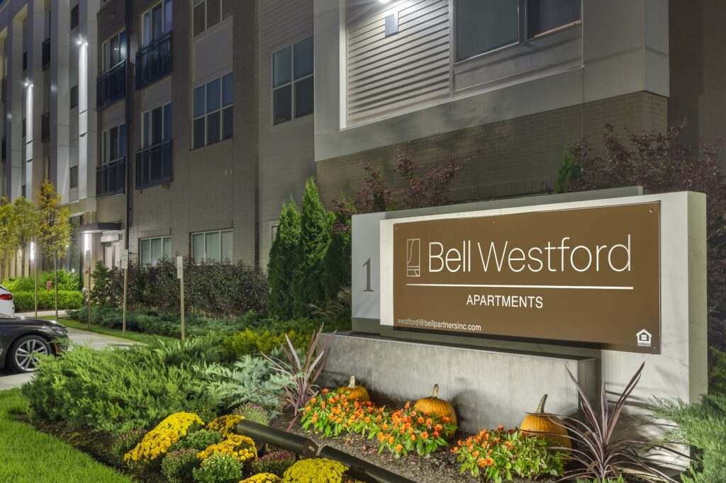 Dusk shot of entrance to apartment complex with Bell Westford sign and garden landscaping