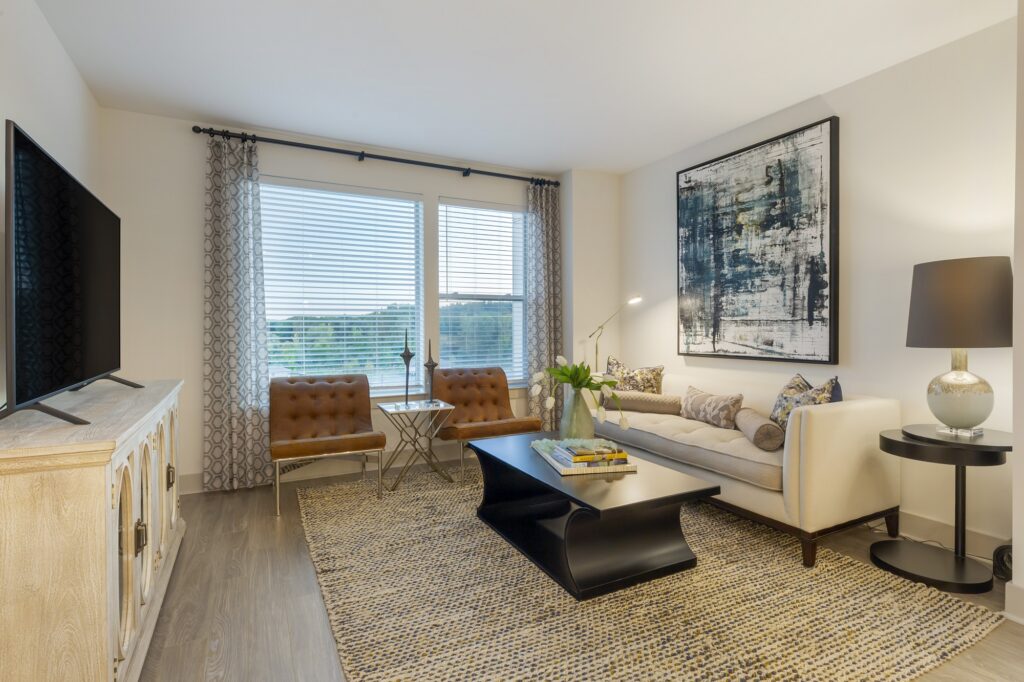 Open concept living room with large flat screen TV, windows, designer lighting, and wood-style flooring