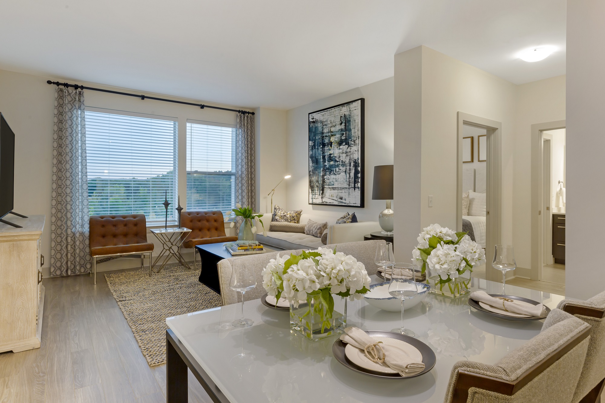 Open concept dining and living room with couch and chair seating, windows, and wood-style flooring