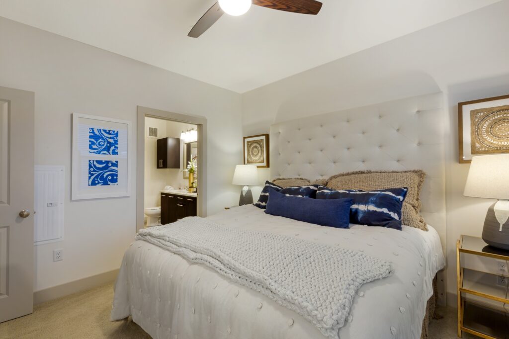 Bedroom with ceiling fan, large window, plush carpet, dresser, king sized bed and nightstands