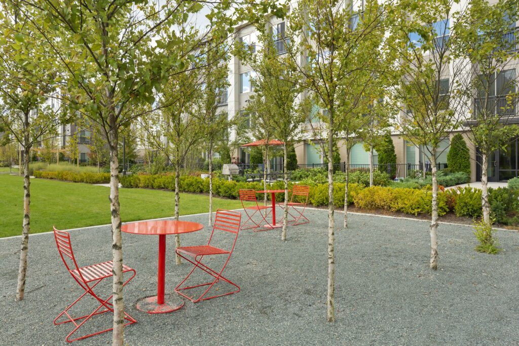 Outdoor picnic seating area with trees and surrounding green landscaping